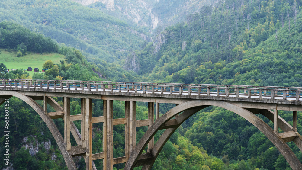 An old concrete suspension bridge over the river on the background of mountains. Panoramic photography, beautiful nature.