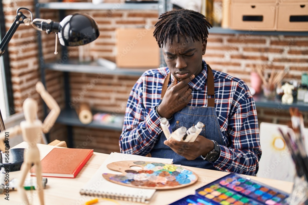 African american man artist choosing color with doubt expression at art studio