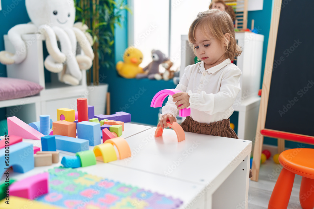 Adorable blonde girl playing with toys standing at kindergarten Adorable blonde girl playing with toys standing at kindergarten