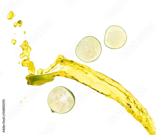 Pouring lime juice down to glass, lime juice fall down in yellow liquid water. Slice green lime in juice throw splash in air. White background Isolated high speed shutter, freeze action