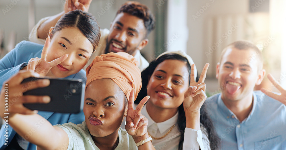 Obraz premium Phone selfie, peace sign and business team in startup office of creative marketing agency. Teamwork, diversity and happy men and women smile for crazy photo on smartphone in modern office.
