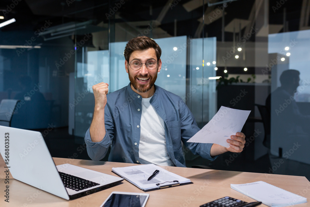 Portrait happy businessman financier, mature man with breed looking at camera and smiling, holding report with good achievement results and financial indicators celebrating victory, triumph gesture