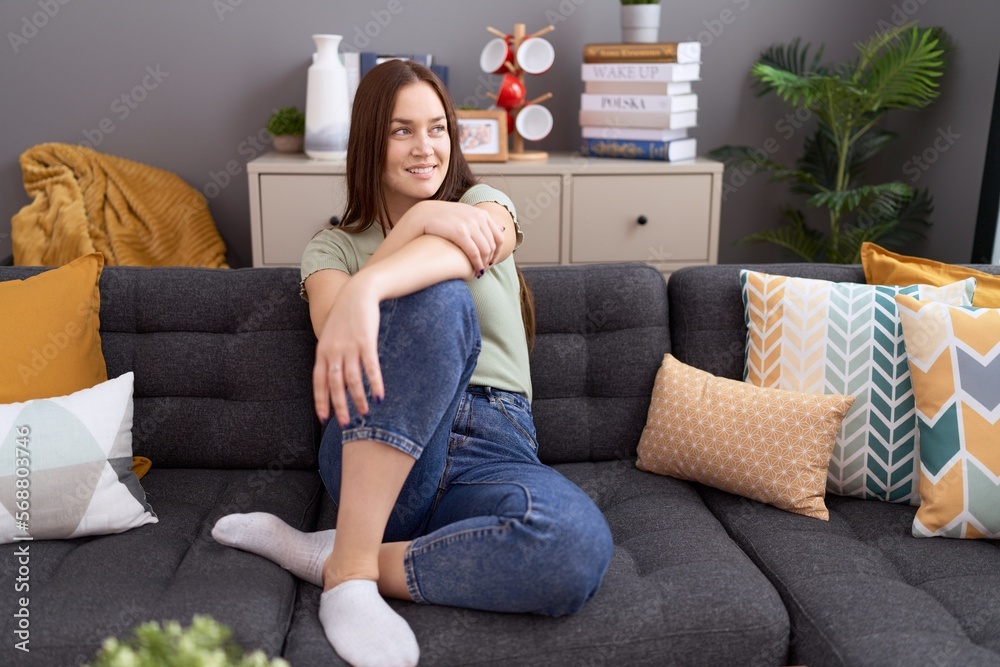Obraz premium Young beautiful woman smiling confident sitting on sofa at home