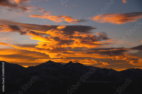 Sunset in the mountains, mountain silhouette against a cloudy sky in orange colors