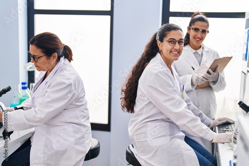 Three woman scientists holding sample write on checklist at laboratory