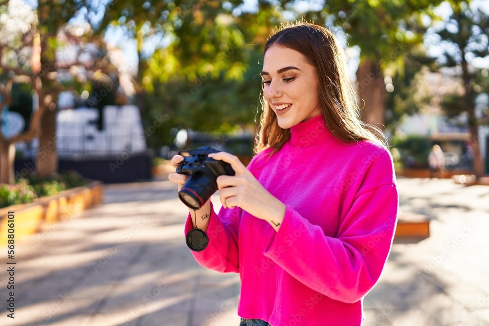Young woman smiling confident using professional camera at park