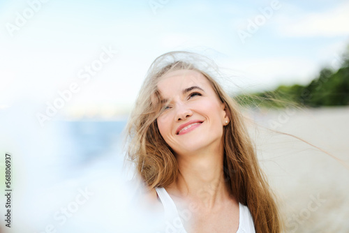 Portrait of a happy smiling woman in free happiness bliss on ocean beach enjoying nature during travel holidays vacation outdoors. View through white blurred flowers