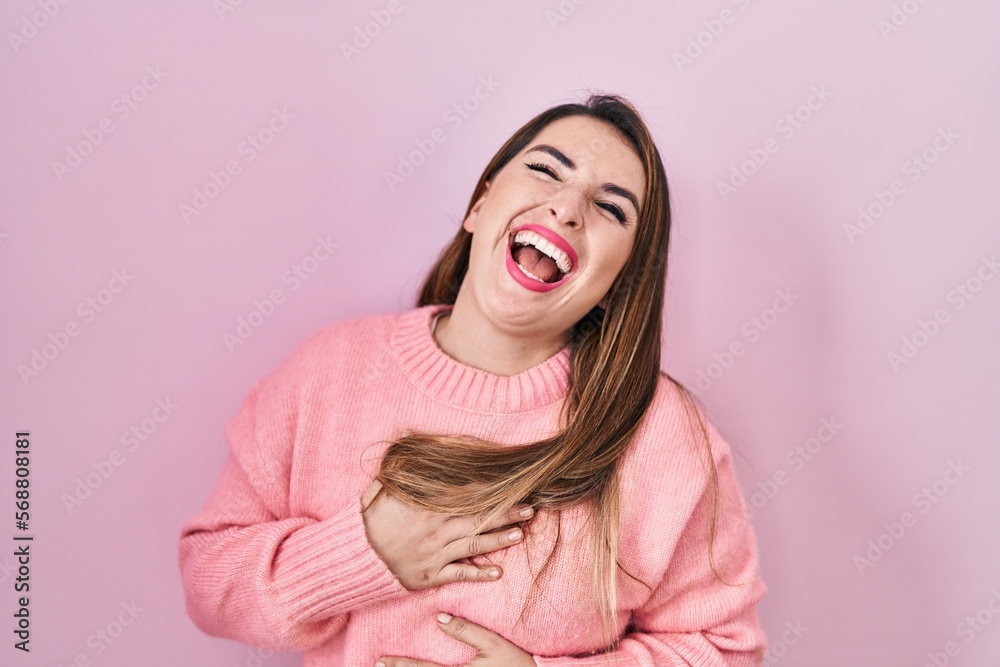 Young hispanic woman standing over pink background smiling and laughing hard out loud because funny crazy joke with hands on body. Young hispanic woman standing over pink background smiling and laughing hard out loud because funny crazy joke with hands on body.