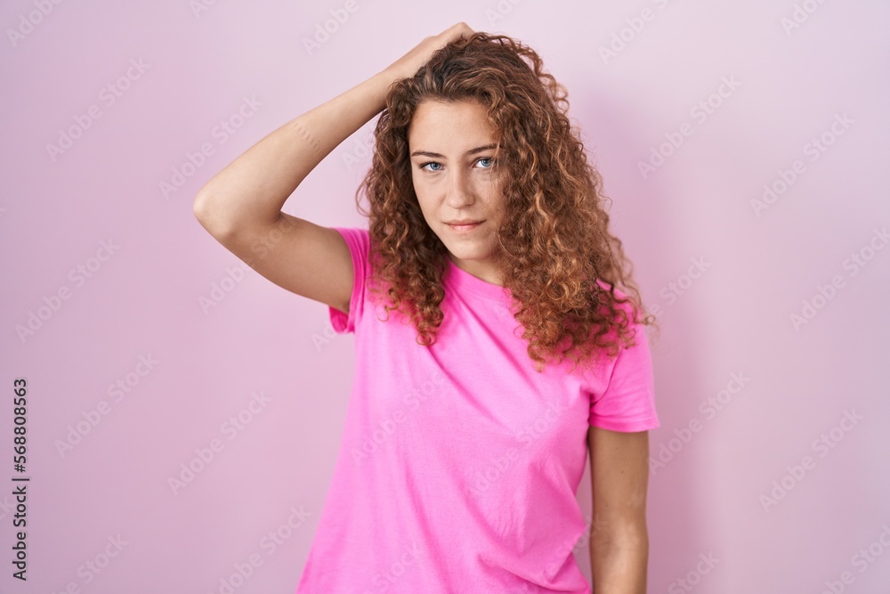 Young caucasian woman standing over pink background confuse and wondering about question. uncertain with doubt, thinking with hand on head. pensive concept.