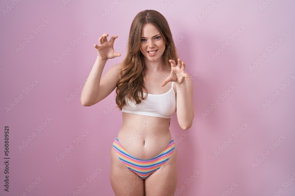 Caucasian woman wearing lingerie over pink background smiling funny doing claw gesture as cat, aggressive and sexy expression Caucasian woman wearing lingerie over pink background smiling funny doing claw gesture as cat, aggressive and sexy expression
