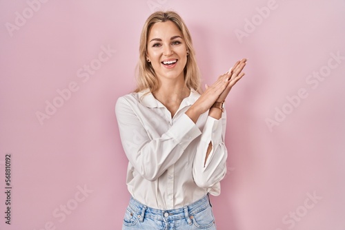 Young caucasian woman wearing casual white shirt over pink background clapping and applauding happy and joyful  smiling proud hands together