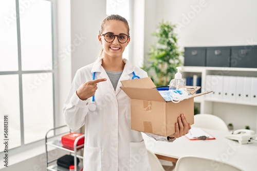 Wallpaper Mural Young doctor woman holding box with medical items smiling happy pointing with hand and finger Torontodigital.ca