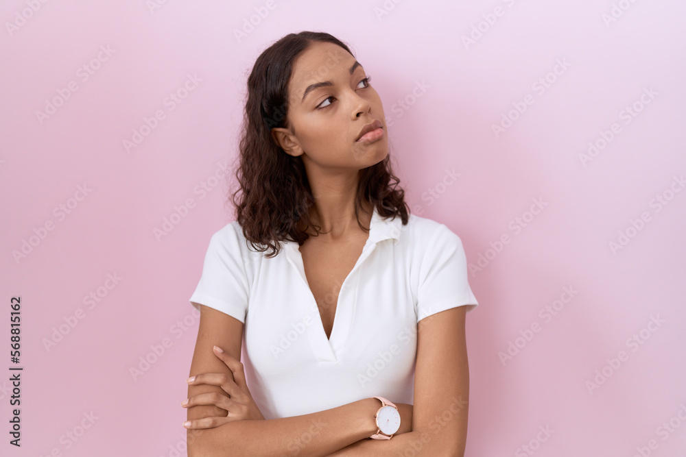 Young hispanic woman wearing casual white t shirt looking to the side with arms crossed convinced and confident Young hispanic woman wearing casual white t shirt looking to the side with arms crossed convinced and confident