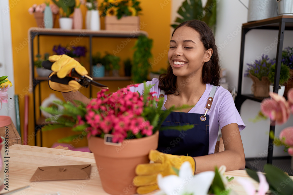 Young african american woman florist cutting plants at flower shop
