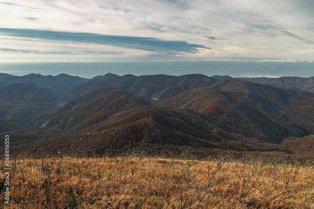 View from a great height in a picturesque place of the Caucasus. The mountain range of the Caucasus against the background of clouds. Beautiful mountain landscape. Mountain pass, mountain range. 