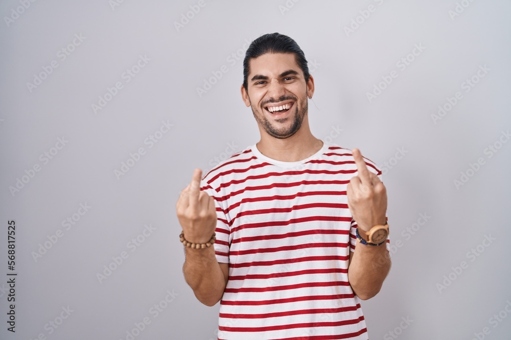 Hispanic man with long hair standing over isolated background showing middle finger doing fuck you bad expression, provocation and rude attitude. screaming excited Hispanic man with long hair standing over isolated background showing middle finger doing fuck you bad expression, provocation and rude attitude. screaming excited