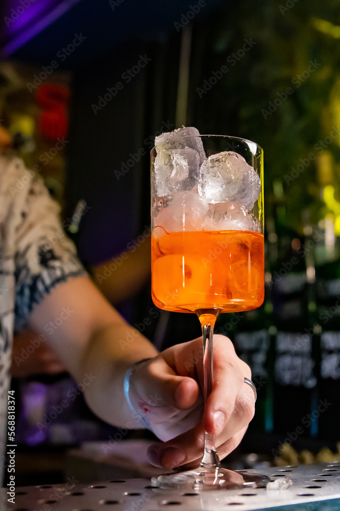 man hand bartender making sweet and sour refreshing Aperol Spritz cocktail on the bar counter