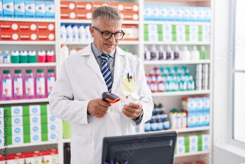 Middle age grey-haired man pharmacist scanning pills bottle at laboratory