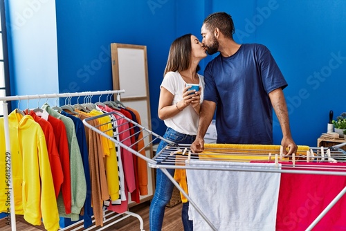 Man and woman couple drinking coffee hanging clothes on clothesline at laundry photo