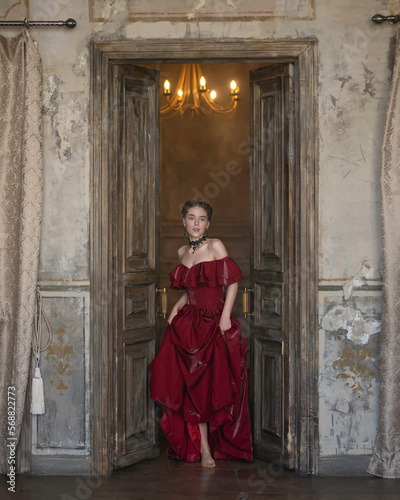 A girl in a red dress enters a wooden door © Evgeniya Fedorova