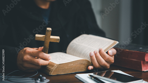 Christian online technology concept. Hands praying of christian with digital computer laptop, Online live church for sunday service. Asian catholic man are reading Holy bible book and online study.