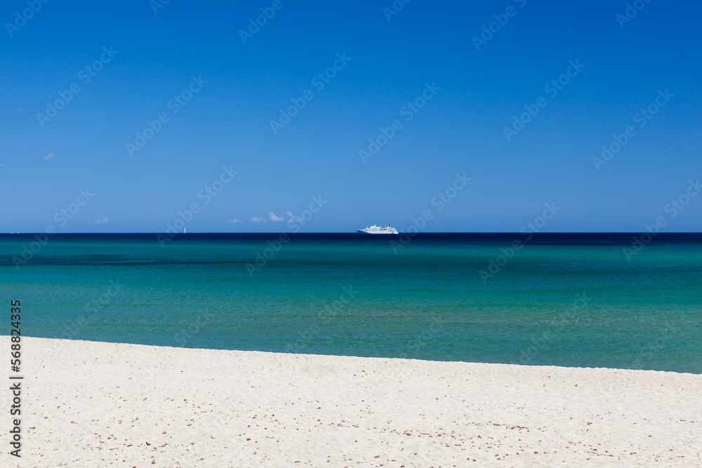 Clear turqoise water of Mediterranean sea with blue sky and vessel on horizon at Sardinia, Italy on sunny day. Amazing sea view.