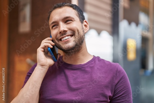 Young man smiling confident talking on the smartphone at street