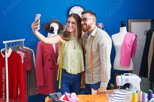 Man and woman tailors smiling confident make selfie by smartphone at clothing factory