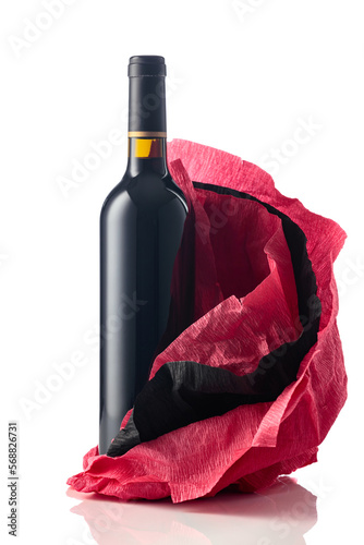 Bottle of red wine with crumpled crepe paper isolated on a white background.