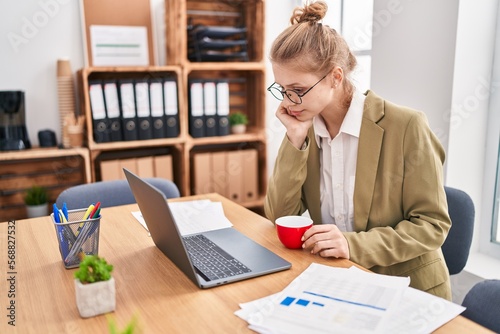Young blonde woman business worker using laptop drinking coffee at office
