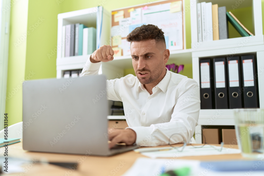 Young hispanic man business worker angry screaming at office