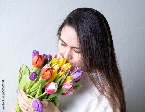 A beautiful young woman without makeup holds a bouquet of tulips. The concept of natural beauty.