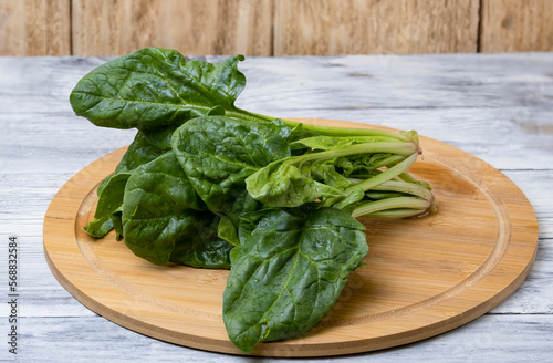Spinach leaves on a wooden plate on a wooden table. The concept of healthy food.