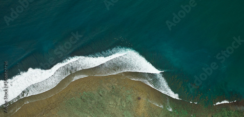 drone shot of a coastline surfspot with blue rough waves an riff at the beach