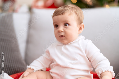 Adorable toddler sitting on sofa with relaxed expression at home