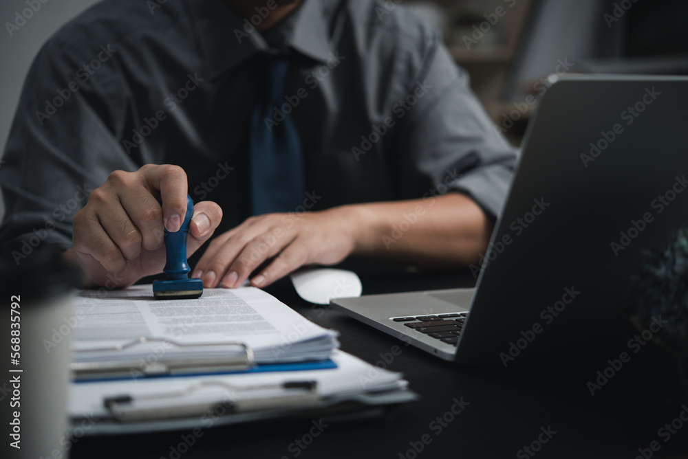 Man hand stamping approval signing on document or paperwork contract at desk. Man hand stamping approval signing on document or paperwork contract at desk.