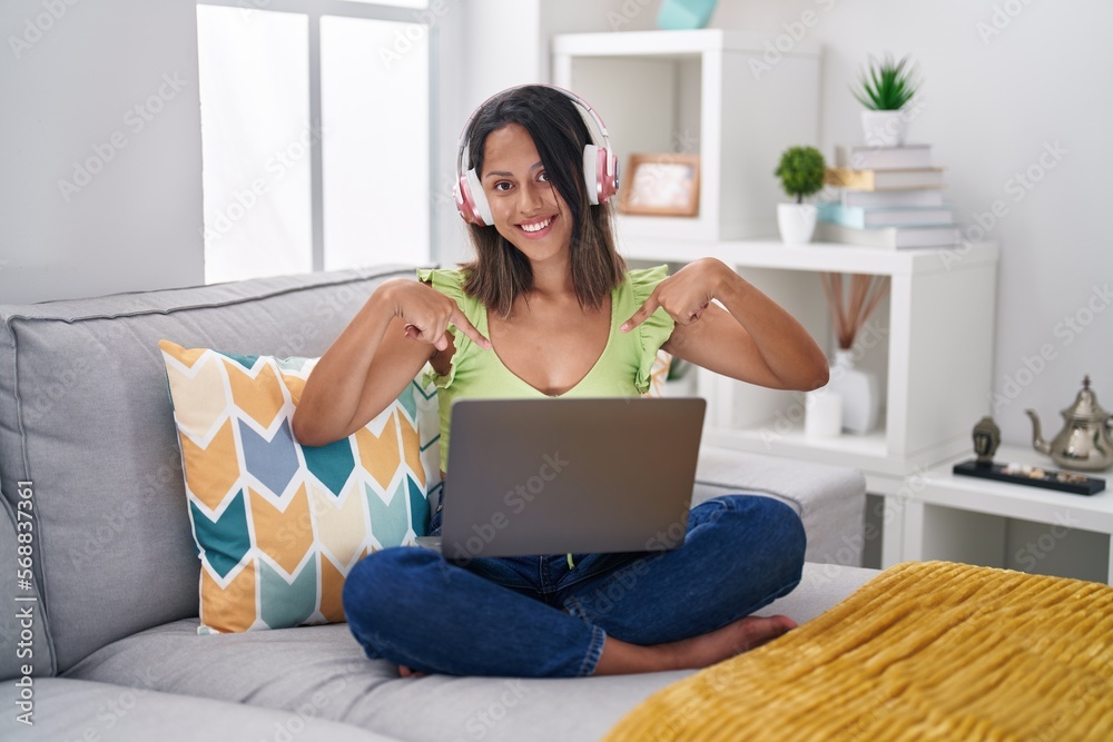 Hispanic young woman using laptop at home looking confident with smile on face, pointing oneself with fingers proud and happy. Hispanic young woman using laptop at home looking confident with smile on face, pointing oneself with fingers proud and happy.