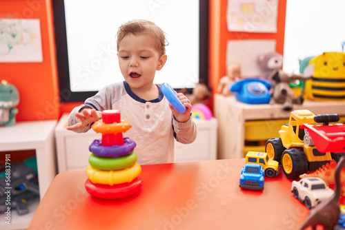 Adorable caucasian boy playing with hoops toy standing at kindergarten