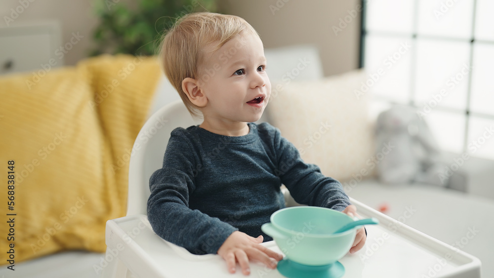 Adorable blond toddler sitting on highchair waiting to eat at home Adorable blond toddler sitting on highchair waiting to eat at home