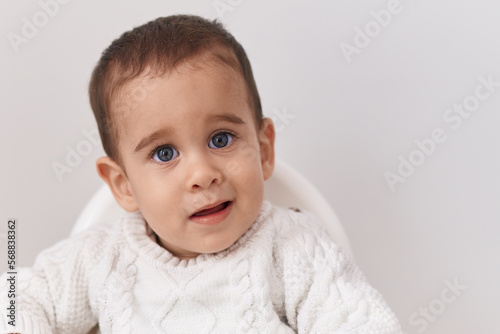 Adorable hispanic toddler smiling confident sitting on highchair over isolated white background