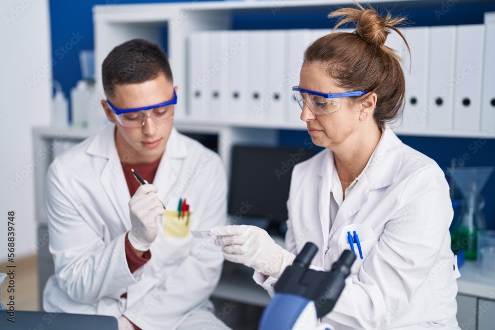 Man and woman scientists looking sample at laboratory Man and woman scientists looking sample at laboratory