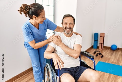 Middle age man and woman smiling confident having physiotherapy session at physiotherapy clinic