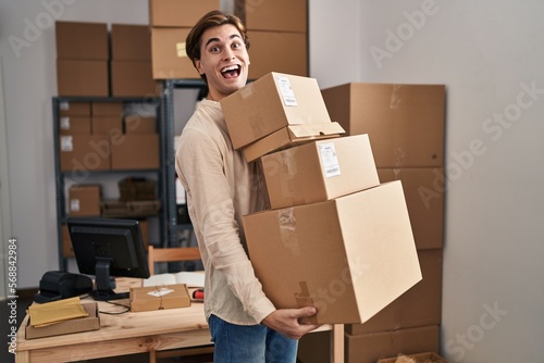 Young man working at small business ecommerce holding packages celebrating crazy and amazed for success with open eyes screaming excited. © Krakenimages.com