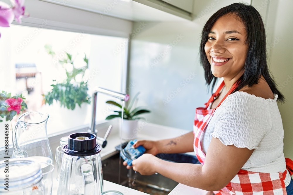 Hispanic brunette woman washing dishes at the kitchen