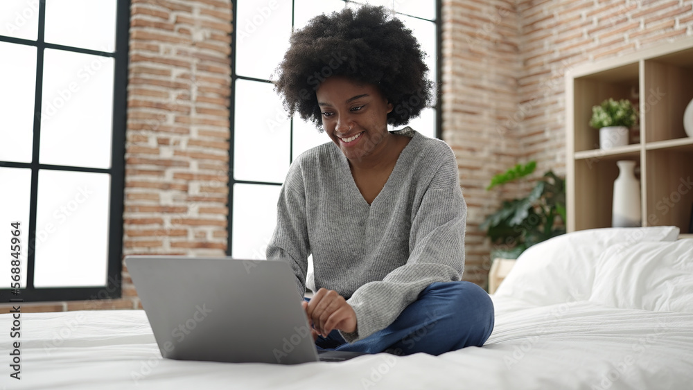 African american woman using laptop sitting on bed at bedroom African american woman using laptop sitting on bed at bedroom