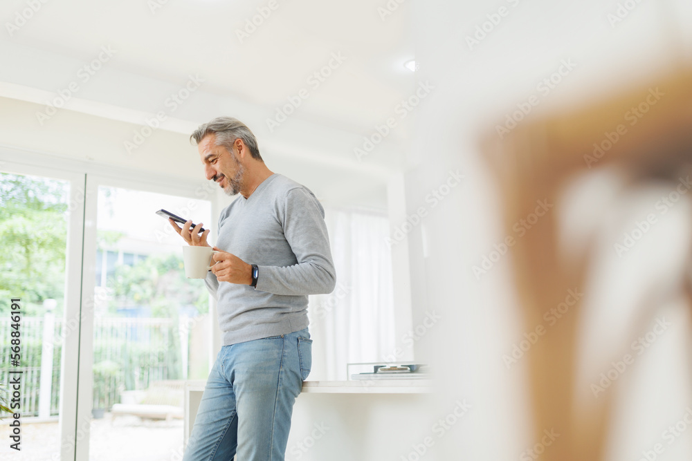 Mature Adult man using mobile phone or smartphone at home. Senior male having video call with his family or friends in the morning.