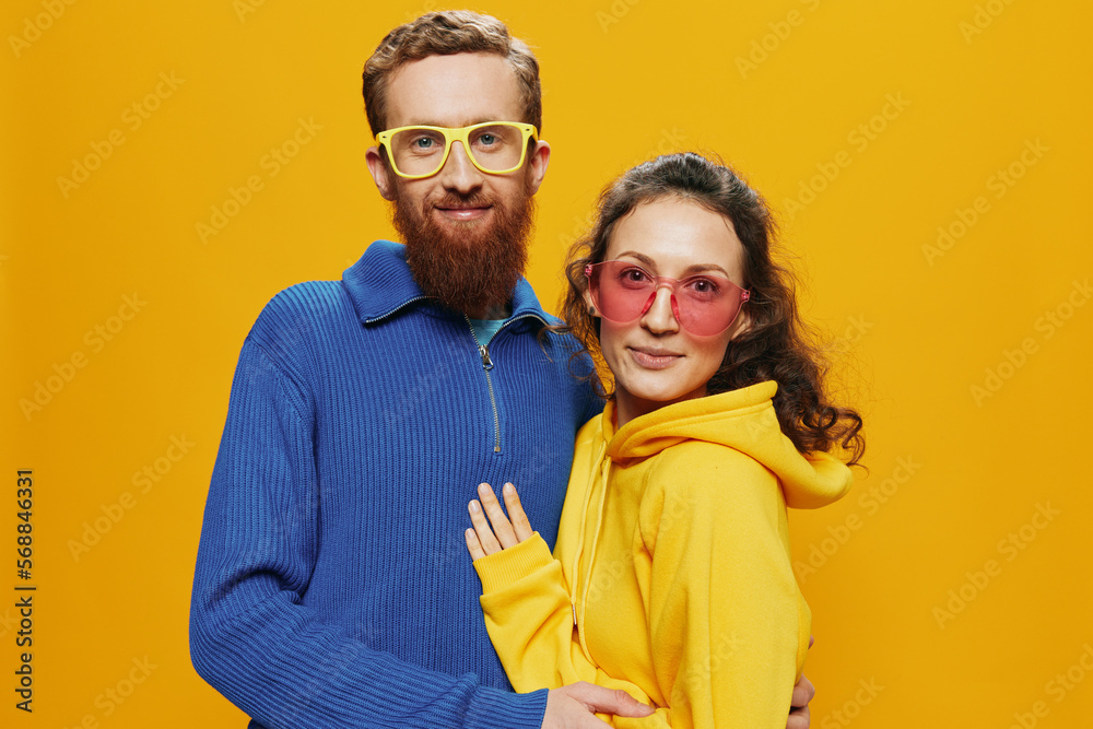 Fototapeta premium Man and woman couple smiling cheerfully and crooked with glasses, on yellow background, symbols signs and hand gestures, family shoot, newlyweds.