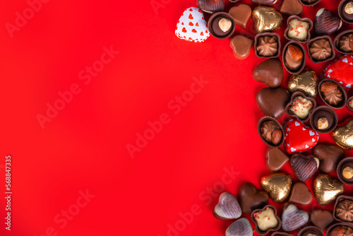 Valentines Day chocolates banner, background, frame. Various sweets and chocolate candy on red paper background with copy space. Romantic composition. Happy Valentine's day greeting card background