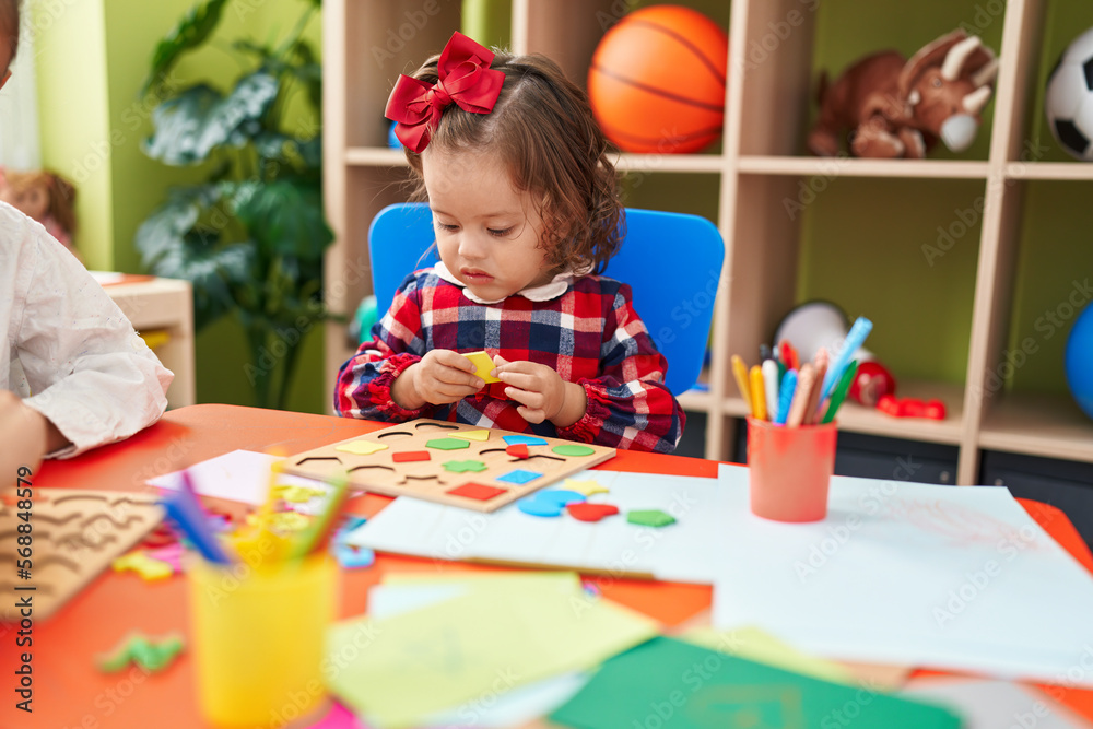 Adorable blonde toddler playing with maths puzzle game sitting on floor at kindergarten Adorable blonde toddler playing with maths puzzle game sitting on floor at kindergarten