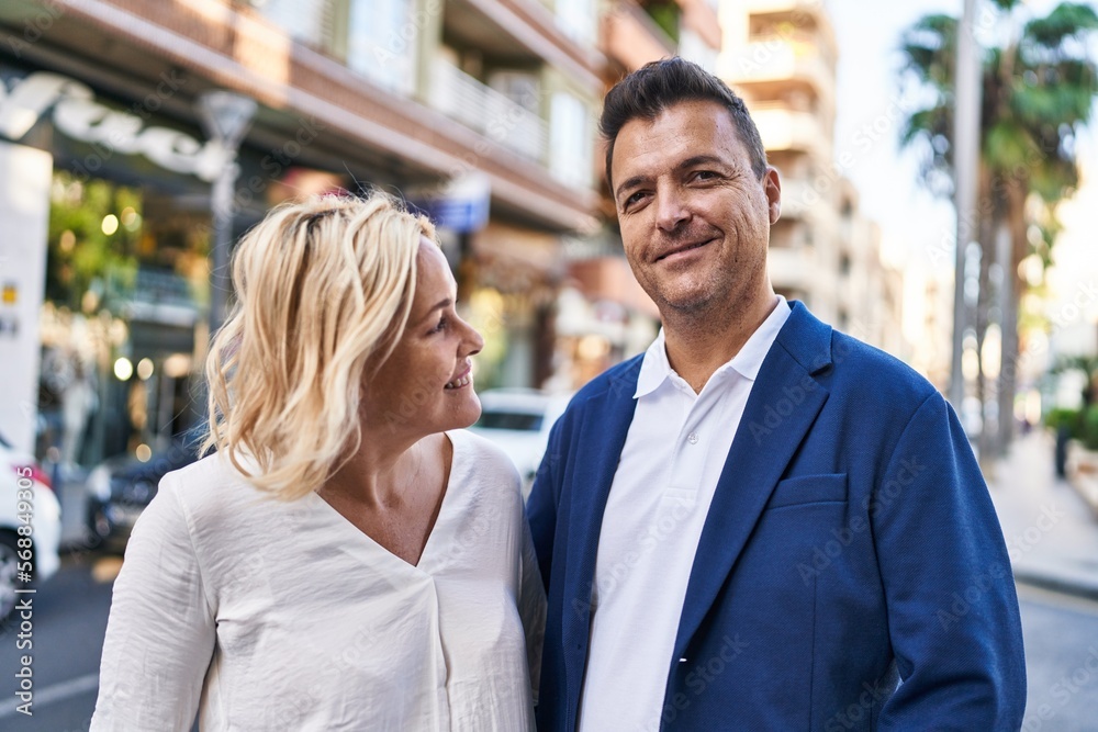 Middle age man and woman couple hugging each other standing at street Middle age man and woman couple hugging each other standing at street